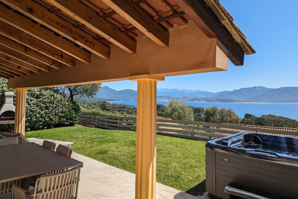 A covered outdoor area with a view of a lake and mountains.