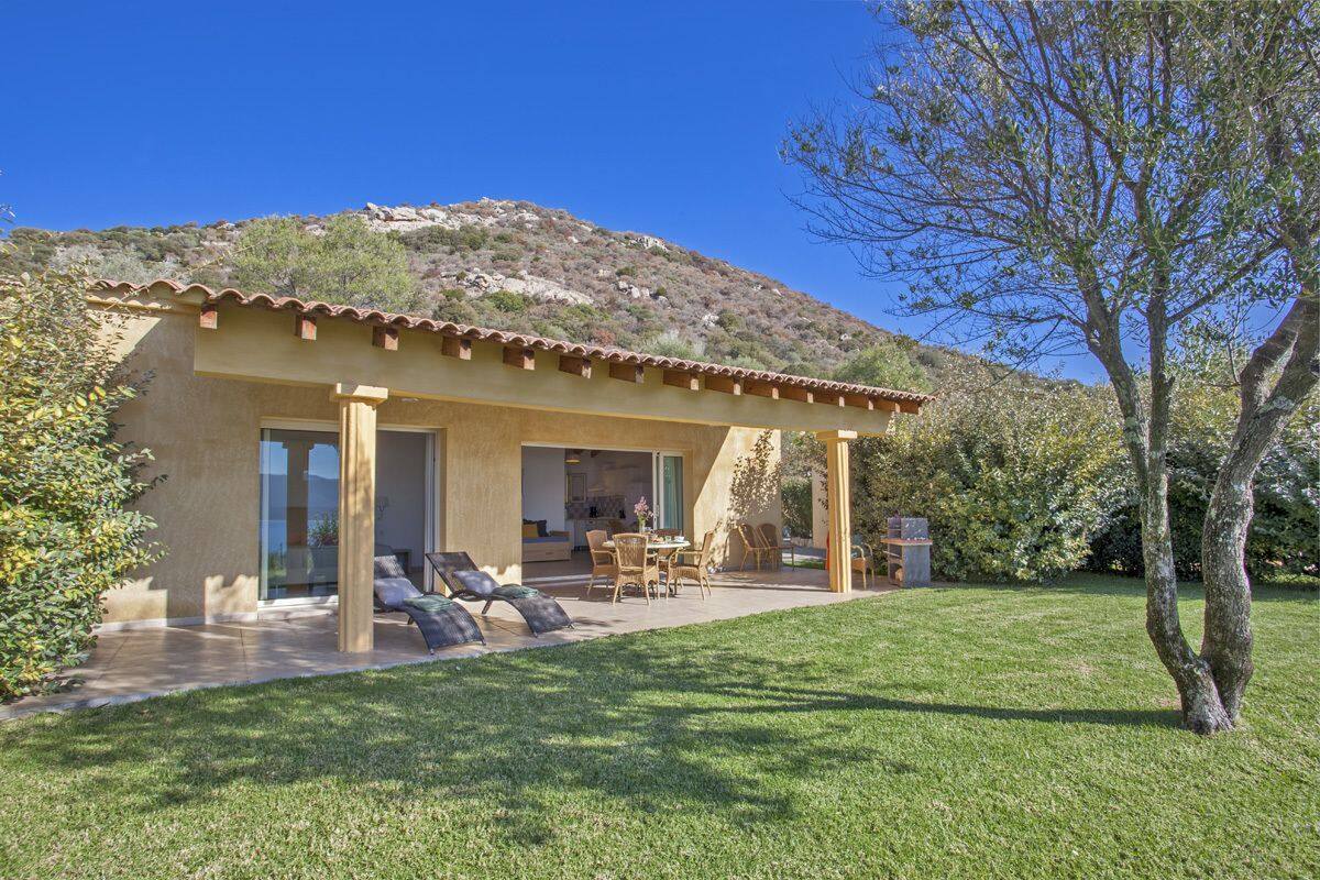 A modern house with a patio, a dining area, and a view of a hillside.