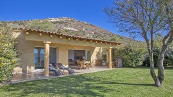 Une maison moderne dotée d’un patio, d’un coin repas et offrant une vue sur une colline.