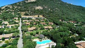A hillside residential area with multiple houses, a central road, and a swimming pool. - Résidence La Plage (Olmeto)