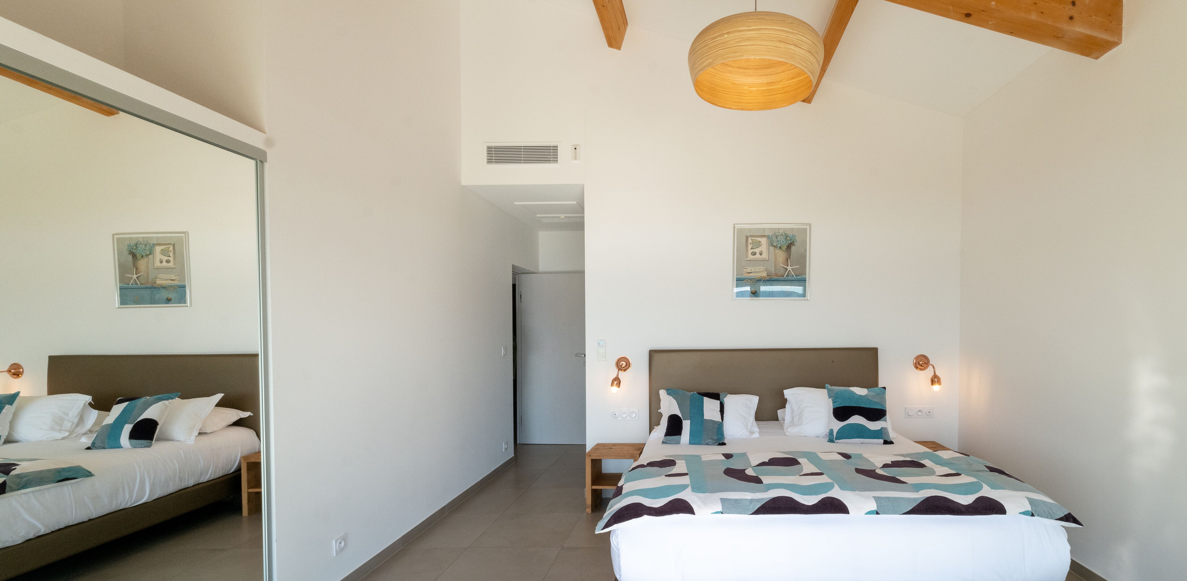 A bedroom with a bed, bedside tables, a mirror, and a ceiling light fixture.