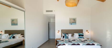 A bedroom with a bed, bedside tables, a mirror, and a ceiling light fixture.