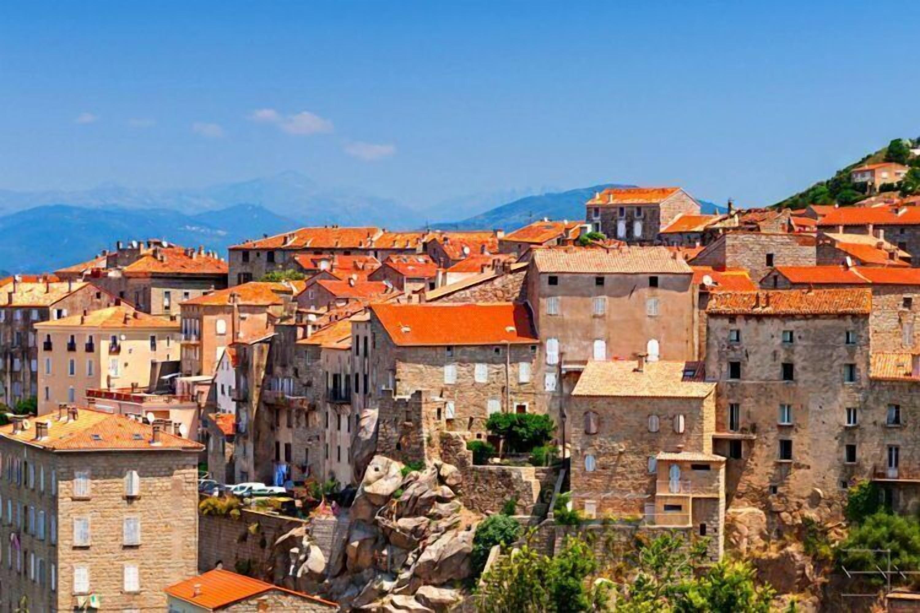Un poble històric amb edificis de pedra i teulades vermelles.