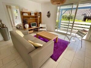 Ein Wohnzimmer mit einer Couch, einem Couchtisch und einem Fernseher auf einem Holzboden.