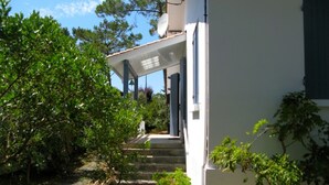 A white building with a covered porch and a staircase leading to a door. - Perfect holiday home in Hourtin-Plage with wifi and very close to the beach (Hourtin)