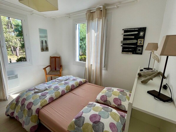 A bedroom with a bed, a chair, a desk, and a window.