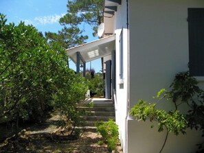 En hvid bygning med en overdækket veranda og trapper op til en dør.