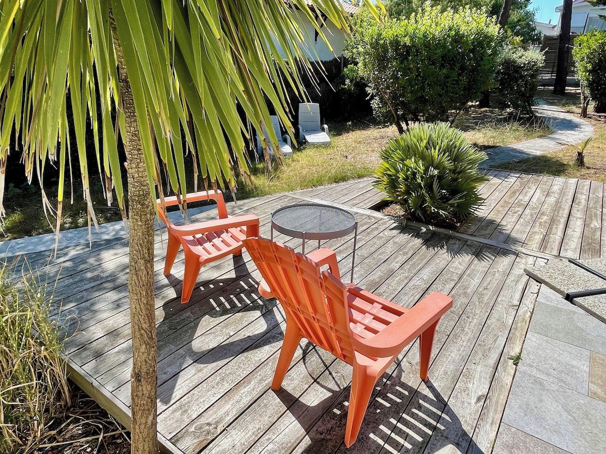 Une terrasse en bois aménagée avec du mobilier d’extérieur, notamment deux chaises et une table.
