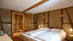 Un dormitorio con techo de madera, una cama con ropa de cama blanca y dos lámparas de noche.