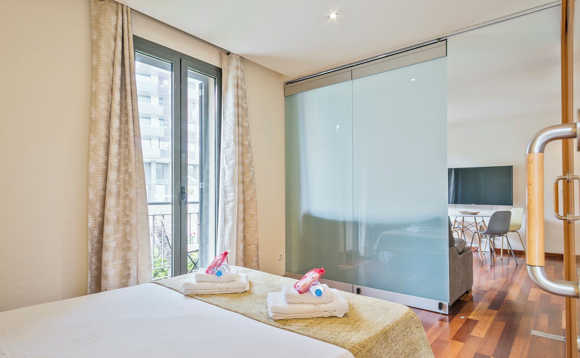 A hotel room with a bed, a bathroom, and a view of the city.