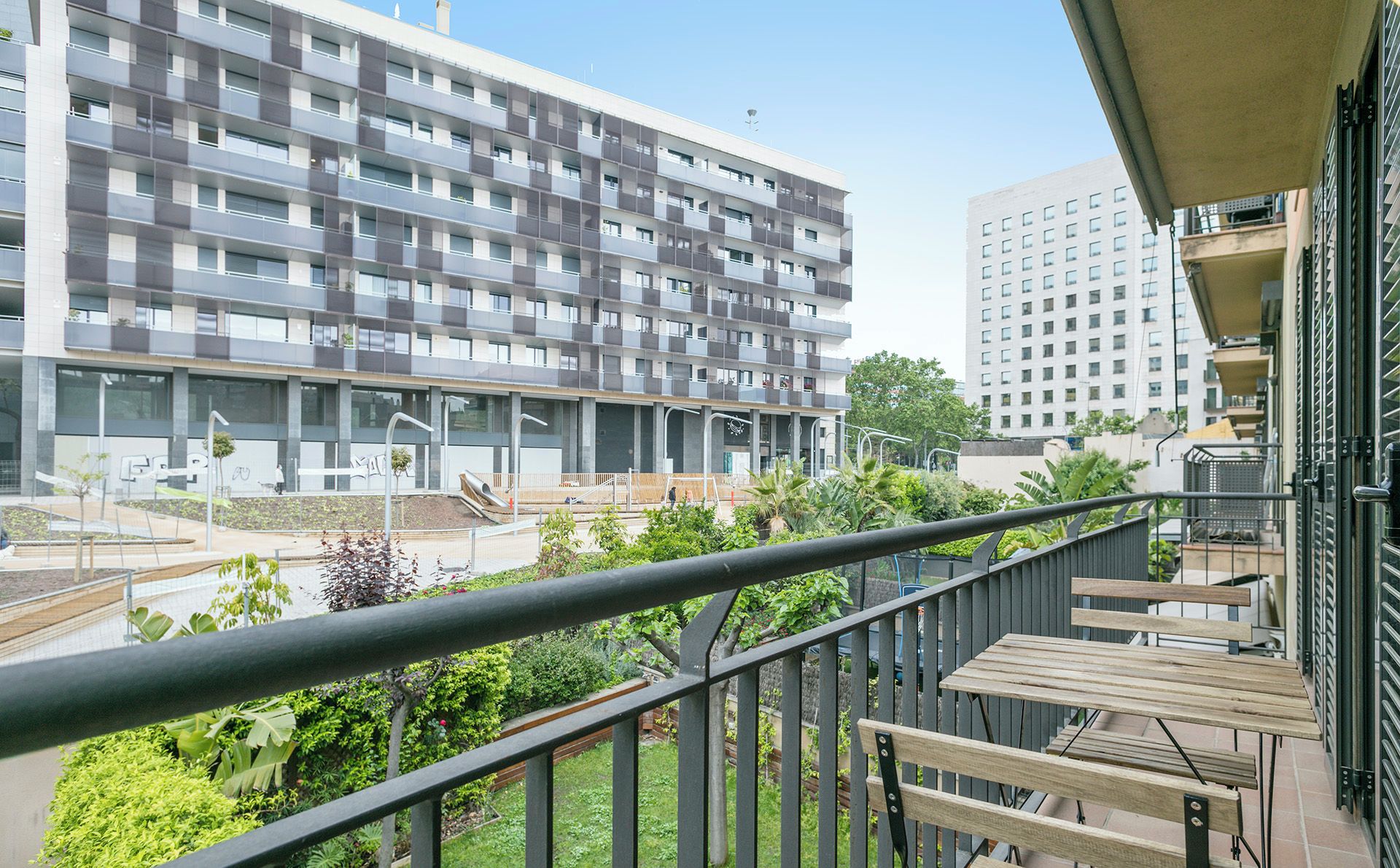 Un moderno edificio de apartamentos con balcones, un jardín en la azotea y vistas a un edificio vecino.