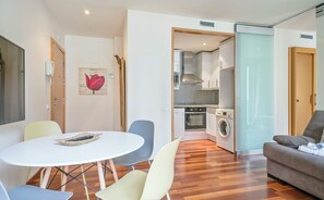A modern living room with a dining area, a sofa, and a kitchen with appliances. - Alcam Anglesola (Barcelona)