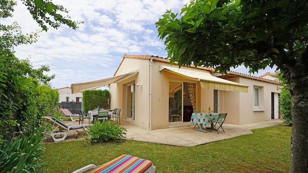 A house with a patio, a covered outdoor seating area, and a lawn.