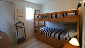 A bunk bed room with a wooden ladder, a desk, and a lamp.