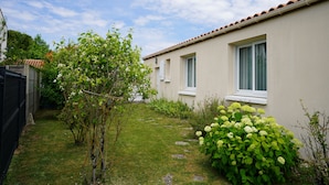 A residential property with a well-maintained garden, a pathway leading to the house, and a tiled roof.