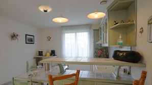 A kitchen with a dining table, chairs, a microwave, and a radio.