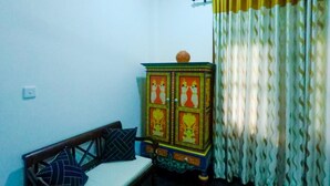 Una habitación con un banco de madera, un aparador con pinturas religiosas y una cortina.