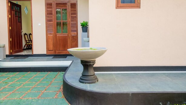 Un patio con una fuente de piedra, puertas de madera y una planta en maceta.
