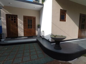 A modern building with two wooden doors, a small white planter, and a circular stone feature. - Halcyon Rest (Hikkaduwa)