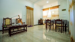 Amplia sala de estar con una mesa de centro de madera, sillas, una guitarra y una mesa de comedor preparada para cuatro.