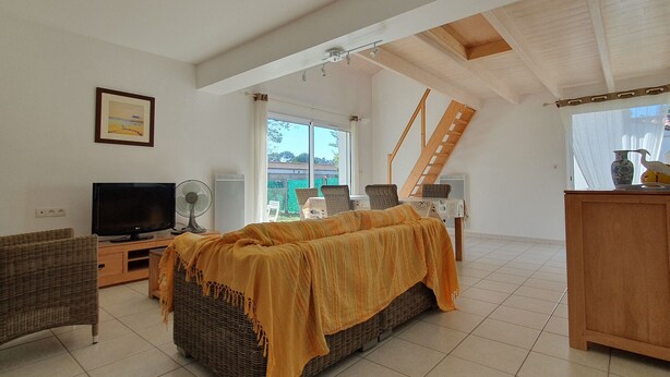 A spacious living room with a large bed, a television, and a staircase leading to an upper level. - Spacious villa near beach, 5 people, private garden (La Faute-sur-Mer)