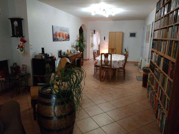 A cozy living room with a dining area, a bookshelf, and a large window. - Magnificent villa for a quiet holiday (Fuveau)