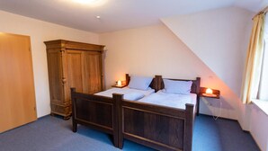 Un dormitorio con una cama de madera, un armario y una mesita de noche con una lámpara.