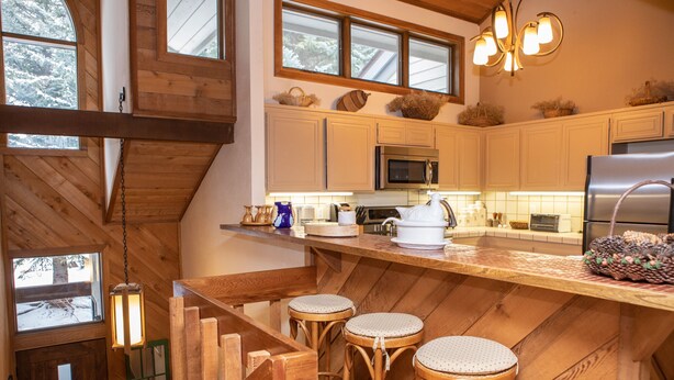 A kitchen with wooden cabinets, a microwave, a refrigerator, and a wooden island with stools. - 126 Ridgepoint 3 Bedroom Townhouse by RedAwning (Avon)