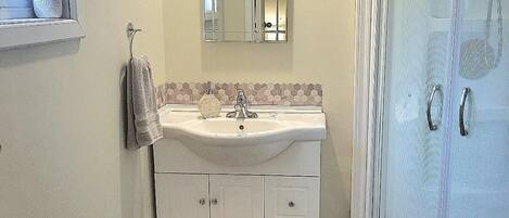 Un baño con lavamanos, espejo y ducha.
