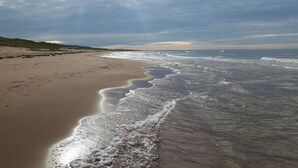 Una spiaggia con un'ampia riva sabbiosa e onde calme.