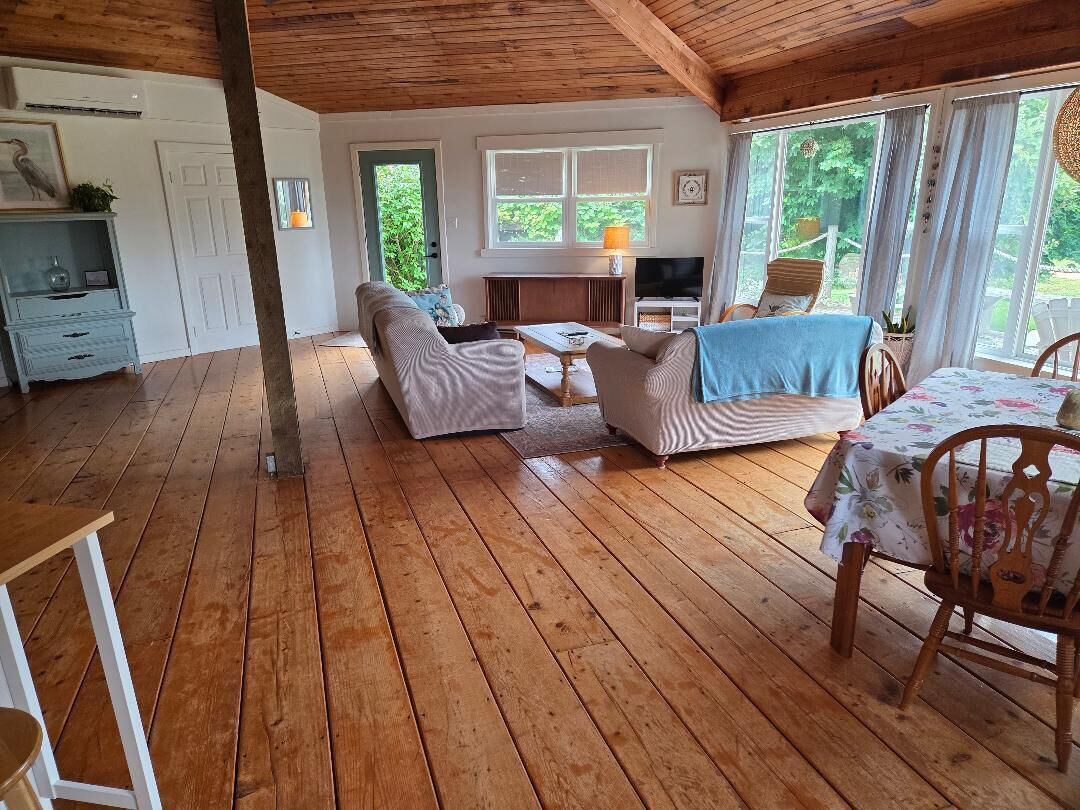 A wooden-floored living area with a sofa, a table, and a TV.