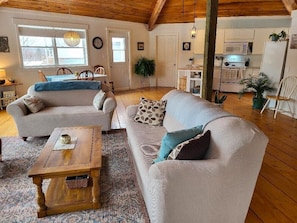 A cozy living room with two sofas, a wooden coffee table, and a patterned rug. - Honeycomb Cottage - bright, airy and spacious sanctuary with water view! (Donaldston)