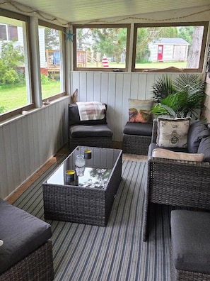 A covered outdoor seating area with wicker furniture, a glass-top coffee table, and a view of the backyard. - Honeycomb Cottage - bright, airy and spacious sanctuary with water view! (Donaldston)