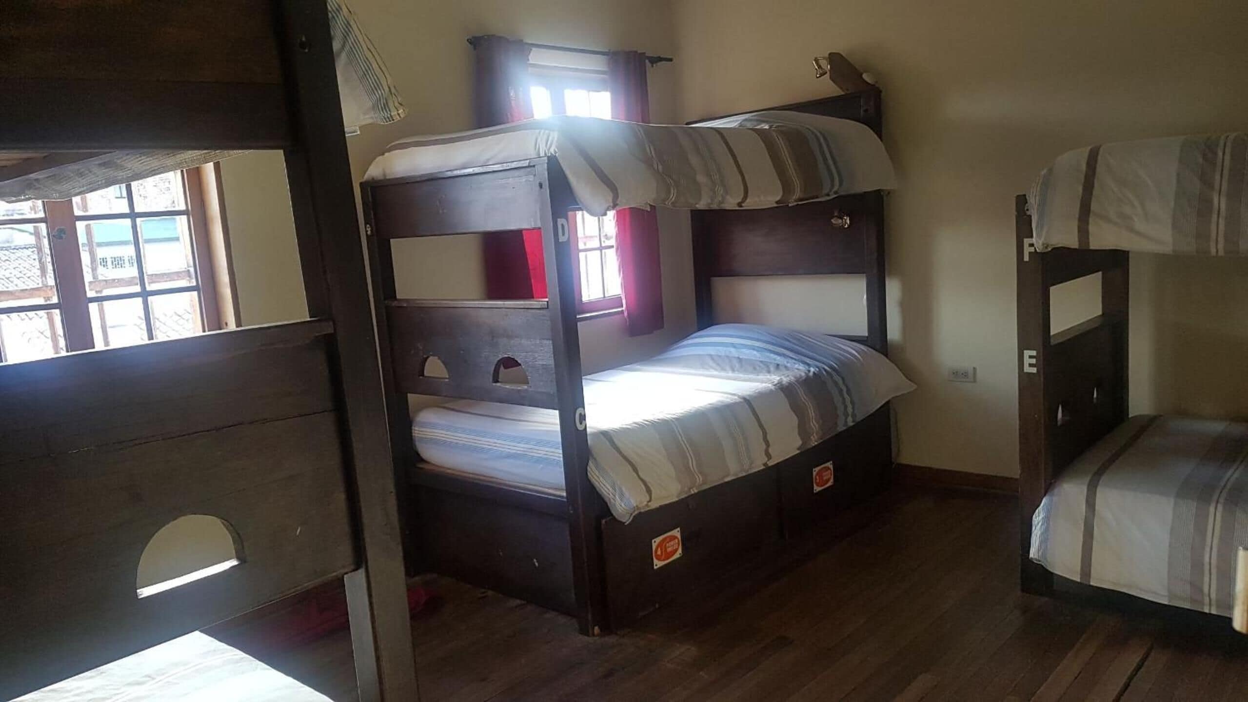 A bunk bed room with a window, a small cabinet, and a door.