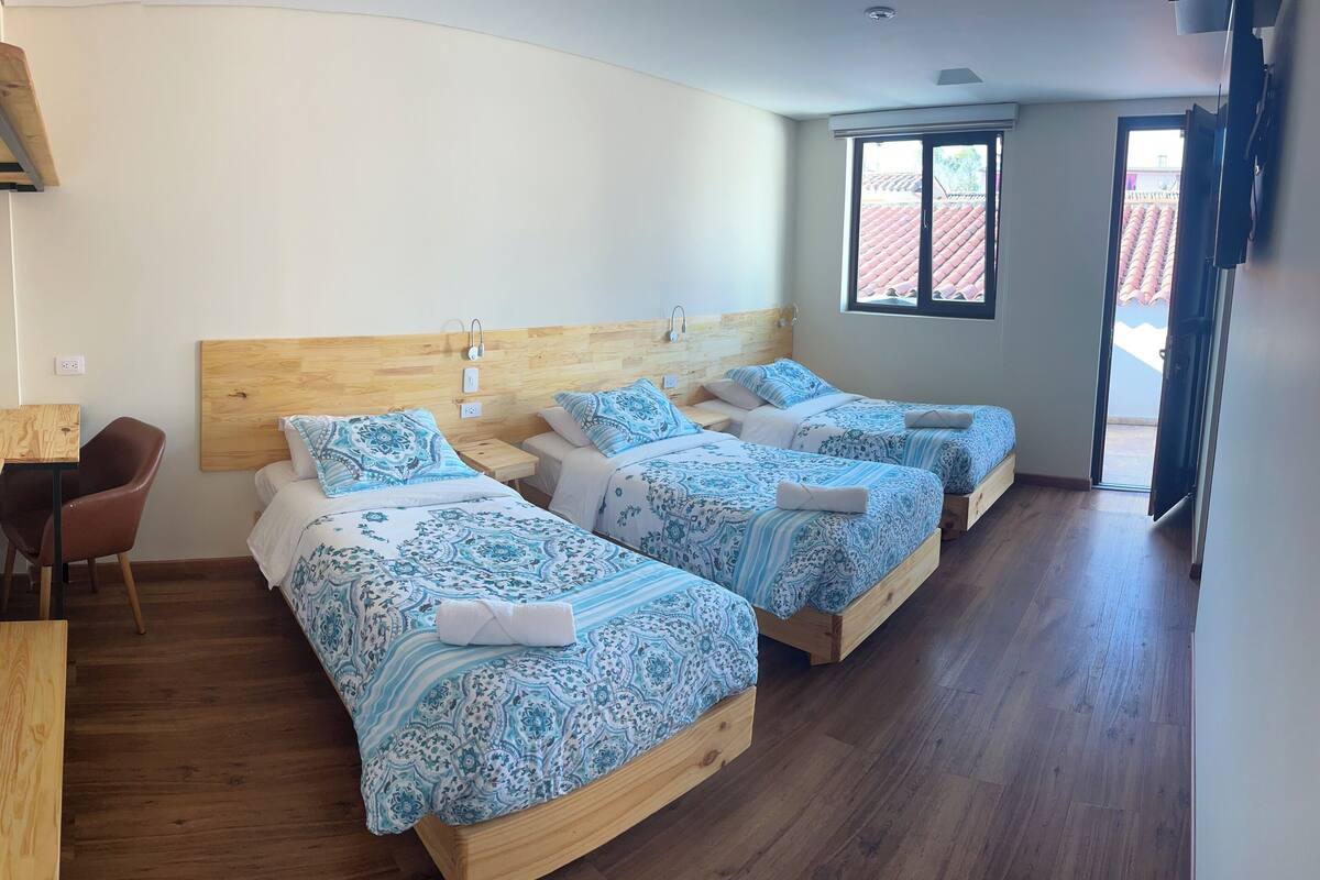 Habitació d'hotel amb dos llits, un escriptori i una cadira.