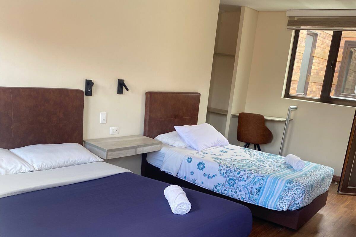 Habitació d'hotel amb dos llits, una taula petita, una cadira i una finestra que dona al carrer.
