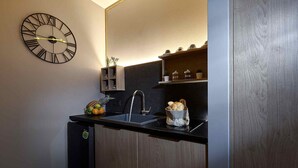 A compact kitchen with a black countertop, a wall-mounted clock, a sink, and a small cabinet with kitchen items. - Seafront Apt Studio with Seaview, infinity pool, beachfront (Limenas Chersonisou)