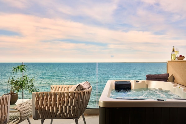 Un balcon avec un jacuzzi, une plante en pot et une vue sur la mer.