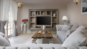 A living room with a large flat-screen TV, a wooden coffee table, a sofa, and a TV stand with shelves. - Villa Luna (Tar-Vabriga)