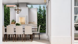 An outdoor dining area with a white table and chairs, a hanging light fixture, and a view of greenery. - Villa Luna (Tar-Vabriga)