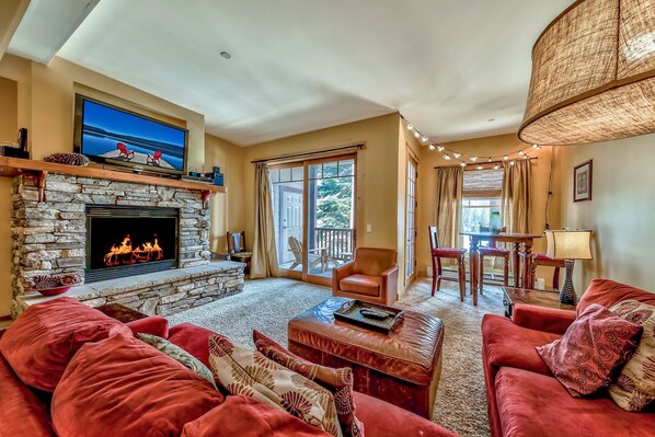Una sala de estar acogedora con chimenea de piedra, sofás rojos y un televisor montado arriba.