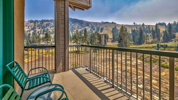 A balcony with a view of a hilly landscape, a metal railing, and two green chairs. - Luxury 2br + Loft, Lodge At Kirkwood Unbeatable Location 2 Bedroom Condo by RedAwning (Kirkwood)
