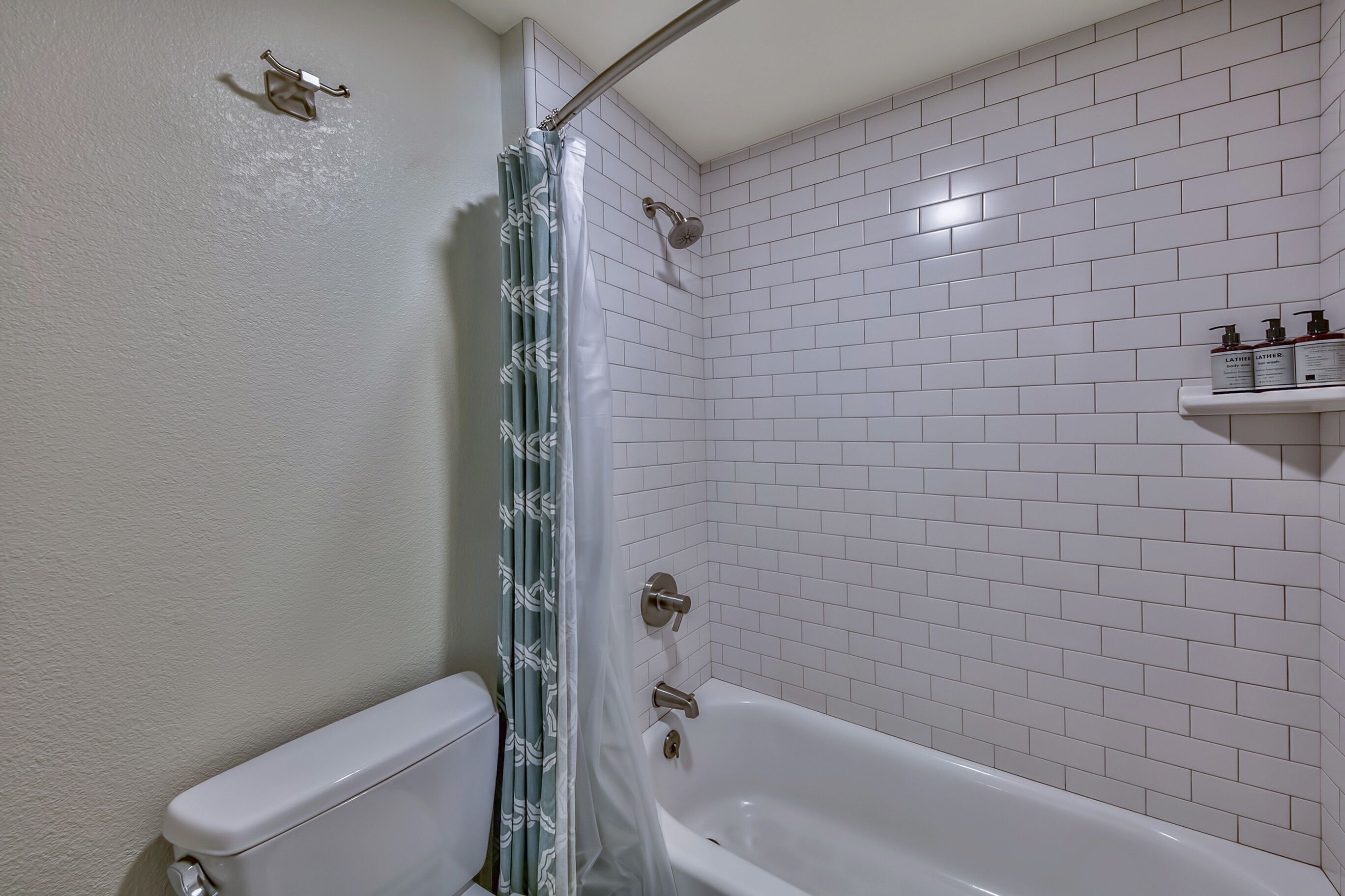 Une salle de bain avec une baignoire blanche, un rideau de douche et des toilettes.