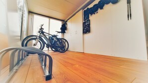 Een kamer met houten vloer, een fiets en een fietsenrek aan de muur.