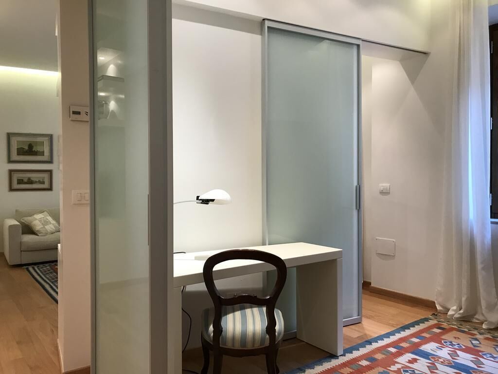 A room with a desk, chair, and a sliding glass door.