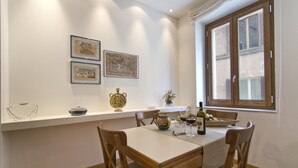 A dining area with a table set for two, a vase, and framed pictures on the wall. - SAN DOMENICO LUXURY APARTMENT (Siena)