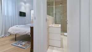 A modern bedroom with a bed, a bedside table, and a TV mounted on the wall. - SAN DOMENICO LUXURY APARTMENT (Siena)
