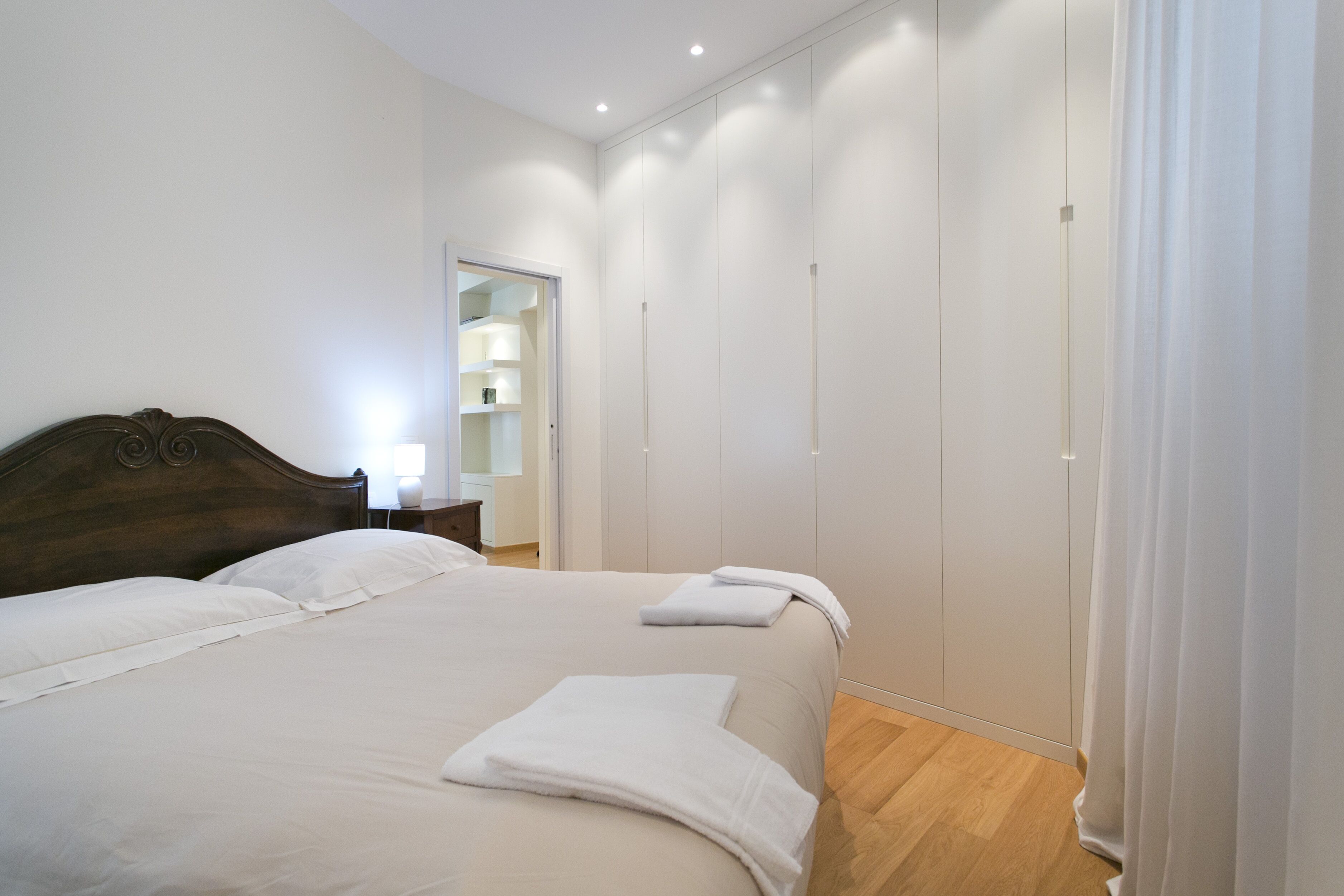Quarto com cama grande, guarda-roupa e mesa de cabeceira.