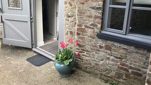 A rustic stone building with a wooden door and a window. - The Pines at Eastleigh - 3 Cottages (Bideford)