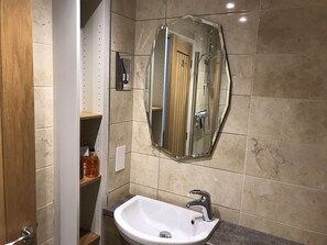 A bathroom with a white sink, a mirror, and a shower enclosure.